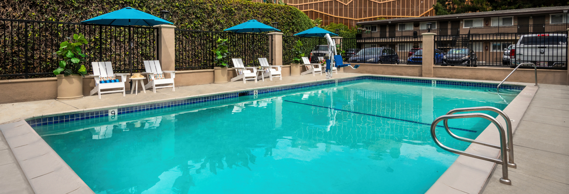 A rectangular outdoor pool with a fenced area and lounge chairs.